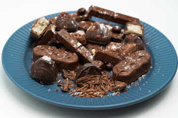 Composition of bars and pieces of different milk and dark chocolate, cocoa grater on a white background, top view