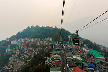 28th March, 2021, Gangtok, Sikkim, India: Tourists enjoying a rope way cable car or Gondola ride over Gangtok city during sunset. Amazing aerial view of Sikkim
