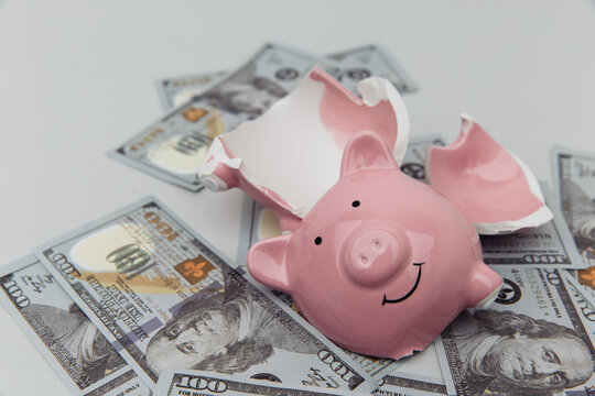 Investment and bankruptcy concept. Broken piggy bank on dollar banknotes