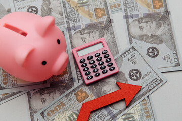 Calculator, arrow up and pyggy bank on dollar banknotes
