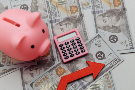 Calculator, arrow up and pyggy bank on dollar banknotes