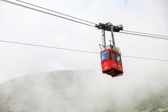 Red funicular or red suspension cable car to Lomnicky peak in fog or clouds, September 2020, High Tatry, Slovakia