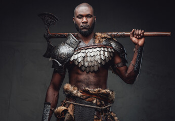 Heroic and wild soldier in steel armor with axe on his shoulders - obrazy, fototapety, plakaty