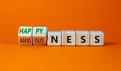 Happyness or anxiousness. Turned cubes and changed the word 'anxiousness' to 'happyness'. Beautiful orange table, orange background. Psychological, happyness or anxiousness concept. Copy space.