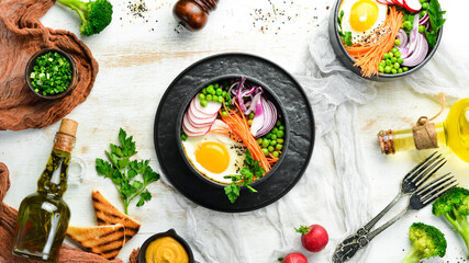 Buddha bowl: egg, green peas, onion, radish and carrots in a black stone bowl.
