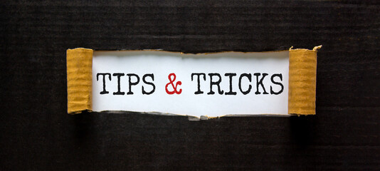 Tips and tricks symbol. Words 'Tips and tricks' appearing behind torn black paper. Beautiful black...