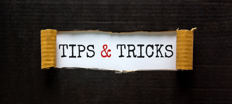 Tips and tricks symbol. Words 'Tips and tricks' appearing behind torn black paper. Beautiful black background. Business, Tips and tricks concept. Copy space.