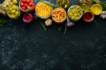 Food stocks in glass jars. Pickled vegetables. On a black background. Top view.