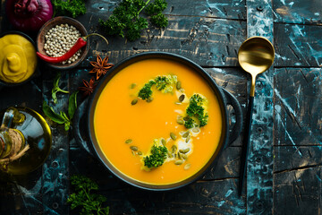 Pumpkin cream soup with pumpkin seeds in a black stone plate. Autumn menu. Diet. Top view. Free...