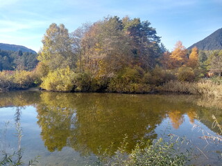 herbstlich bunt gefärbte Bäume spiegeln sich in kleinem See