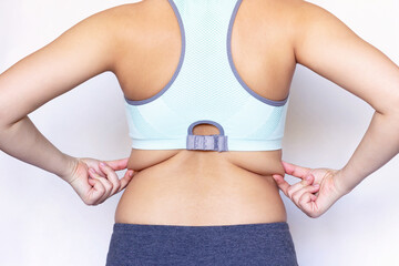 Behind back rear view photo of a young woman holding fat folds on her back. Overweight. Exercises for the back. Body positive