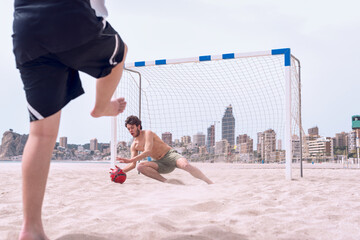 Two boys play soccer on the beach in summer.