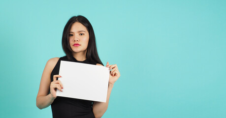 Asian woman is holding blank empty  paper board on green or mint or Tiffany Blue background.