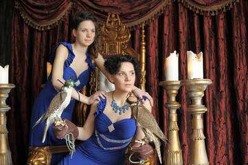 two brunette women princess and queen in blue dress on the throne