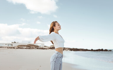 Beautiful young woman breathing fresh air at the beach - 426158497