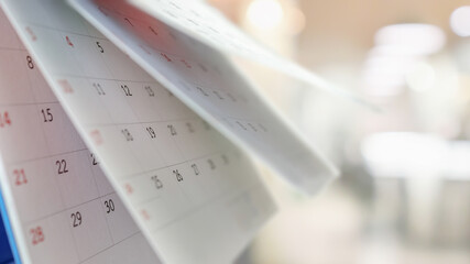 Close up white paper desk calendar with blurred bokeh background appointment and business meeting...