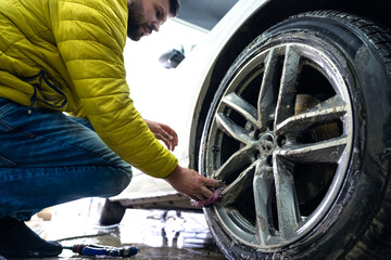 Manual car wheel cleaning with the help of sponges and foam