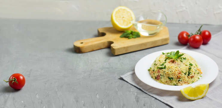 Traditional Arabic salad or Tabbouleh on white plate, cement background. Horizontal banner with copy space