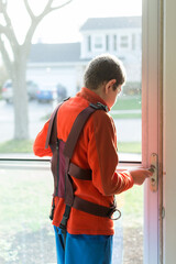 Boy with Autism waiting for school bus; he's wearing a bus harness to keep him safe and seated while riding 