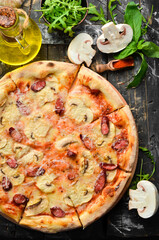 Homemade Pizza with sausages, mushrooms and cheese. On a black stone background. Free space for text.