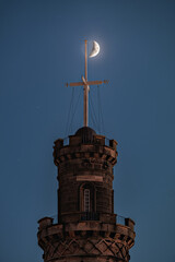 Fototapeta na wymiar The Nelson Monument on Calton Hill at night in front of the crescent moon. Edinburgh, Scotland