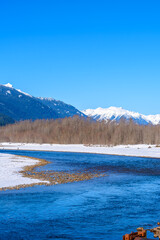 Majestic mountain river in winter over snow mountains and blue sky in Vancouver, Canada.