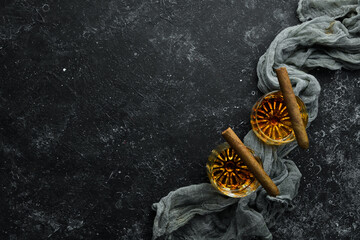 Whiskey in glasses and Cuban cigars on a black stone table. Top view. Free space for your text.