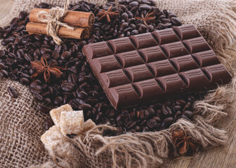 chocolate, coffee beans, anise and cinnamon on wooden background