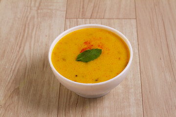 Indian Cuisine Kadhi - Vegetarian Curry Made of Buttermilk And Chick Pea Flour. served in a bowl or Karahi over wooden background, selective focus