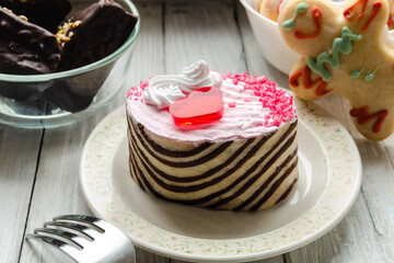 Pink cake with cranberries and whipped cream on wooden background.