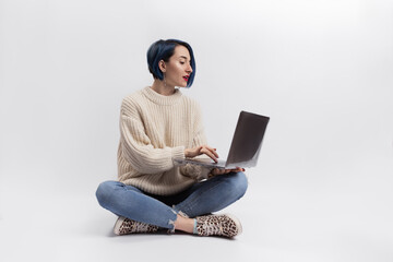 A woman sitting on the floor and holding a laptop
