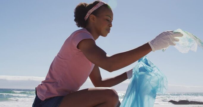African american woman collecting plastic waste on the beach