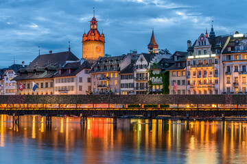 Fototapeta na wymiar Night view towards Chapel Bridge (Kapellbruecke) together with the octagonal tall tower (Wasserturm) it is one of the Lucerne's most famous tourists attraction