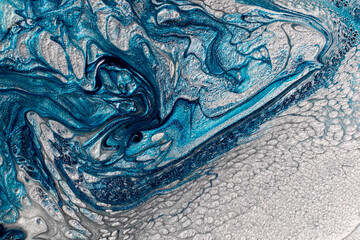 Beautiful shimmer blue and silver stains of liquid nail polish with bubbly texture,looks like ocean wave.Stripy paint texture.Nail lacquer flow modern backdrop. Minimalism concept.Copy space.