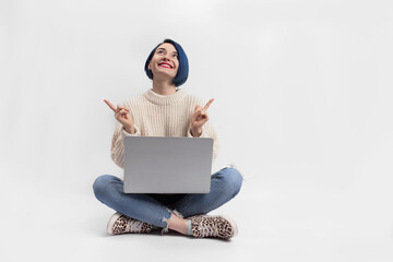 A woman sitting on the floor and holding a laptop