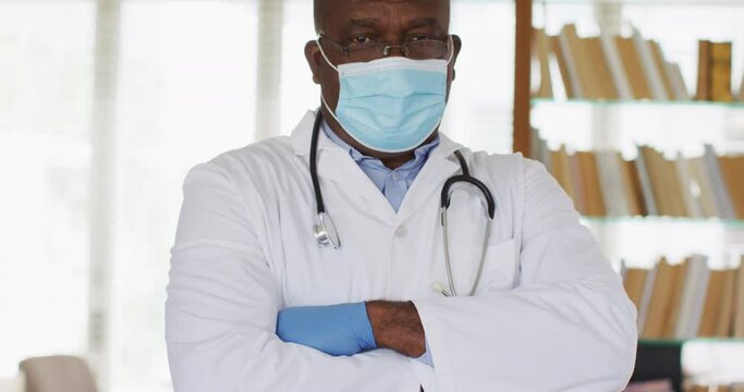 African american senior male doctor wearing white crossing his arms looking at the camera