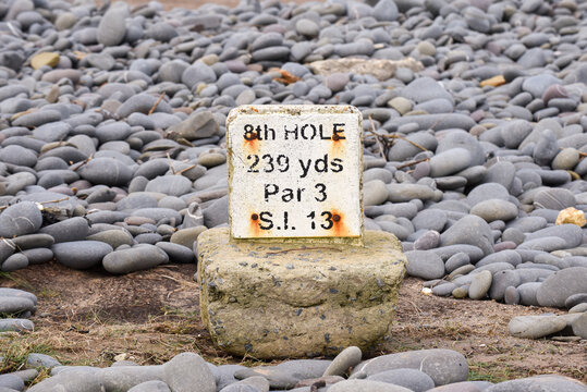 Golf marker sign on a tee which has been washed into the sea