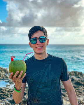 Chico sosteniendo un coco loco con el mar de fondo