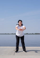 Active and happy senior woman exercising near the riverside