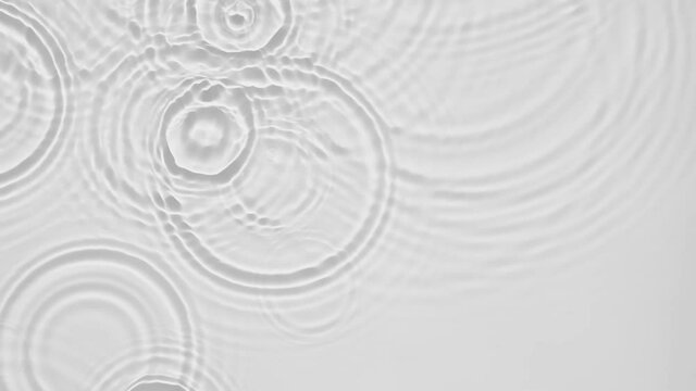 Up close, top view, Slow motion various waves of the water surface hitting the sun's rays, making them sparkle according to different patterns on a gray background video 4K.