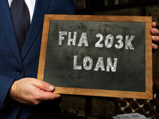 Federal Housing Administration FHA 203K LOAN inscription on the screen. Manager hands holding black...