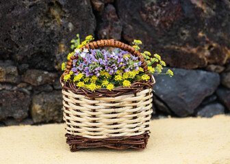 Still life with a bouquet of wild summer flowers in a wicker basket. El Hierro, Canary island, Spain.
