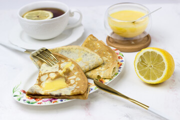 Poppy pancakes stuffed with cream cheese and lemon curd on a white table