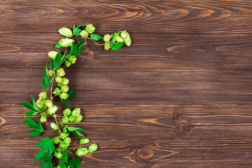 Naklejka premium Hop branch on a dark wooden table. Place for an inscription. Ingredient for beer production