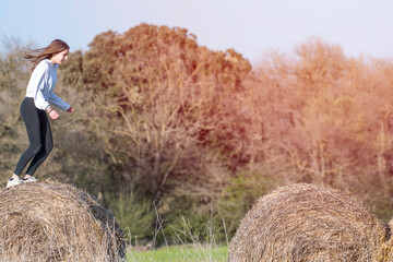 Naklejka na ściany i meble latina teenage girl posing on top of straw bales in rural setting, lifestyle
