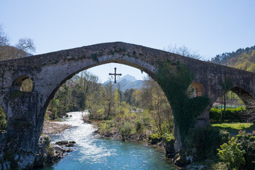 Fototapeta na wymiar Ancient roman bridge at Cangas de Onis, Asturias, with a cross hanging from it as a symbol of victory