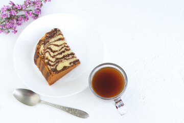 Zebra cake with coffee on white background. Piece of sponge cake on white plate. Copy space.