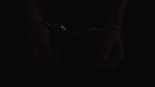 The police take the handcuffed prisoner to the prison. Detention of a suspect. Red and blue light from a police flashers.