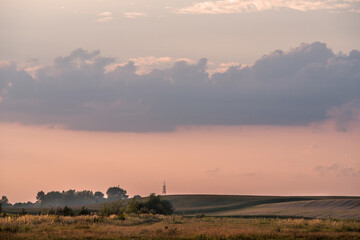 A hilly field. A picturesque sky over a hilly field. Red shade of clouds.