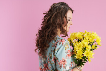 smiling stylish 40 years old woman in floral dress on pink